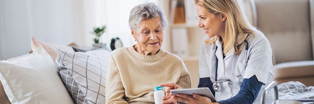 A health care worker performs a home visit with an older patient.