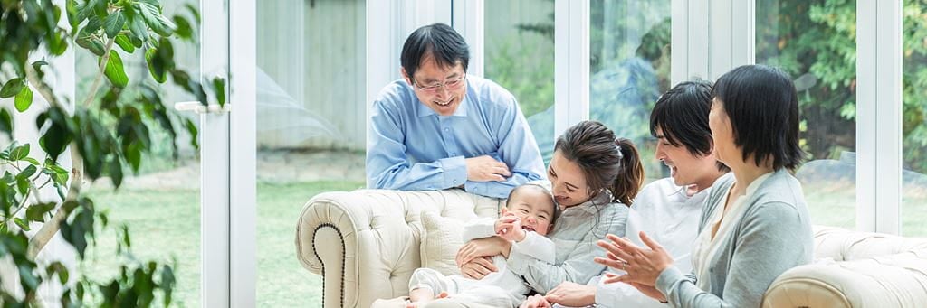 A sandwich generation caregiver sits with her aging parents, partner and newborn child.