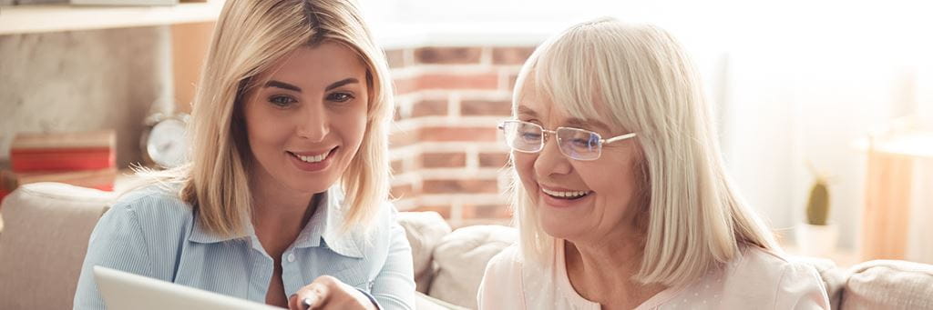 A smiling mother and daughter look at life insurance policies together.