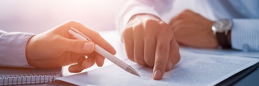 A person holding a pen filling out personal liability insurance forms on a clipboard.