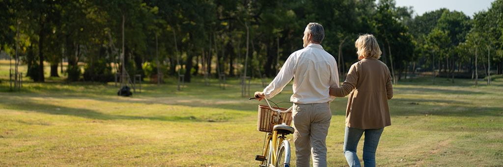 A senior couple walks outdoors while contemplating challenges in retirement.