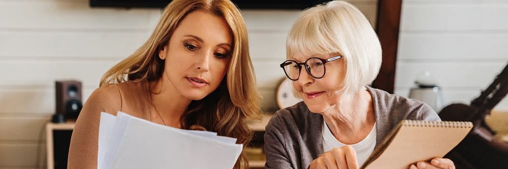 An adult child assists her aging parent with financial documents.