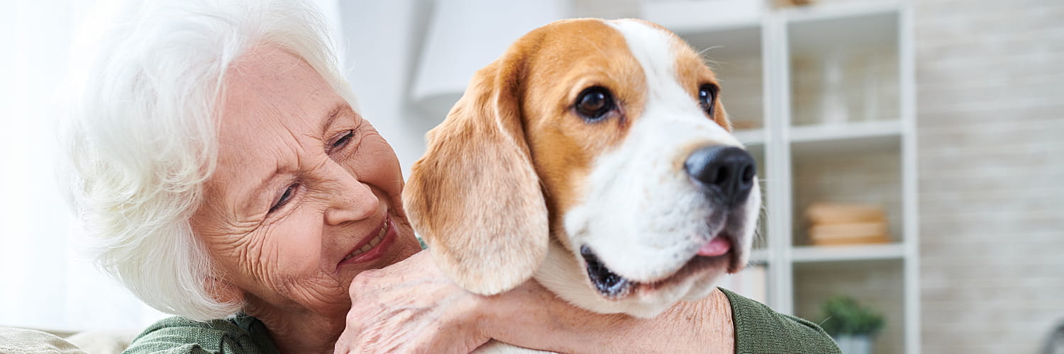 A senior smiling and holding a big dog.