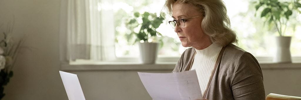 A senior woman on a laptop researches her options for investing in a real estate IRA.