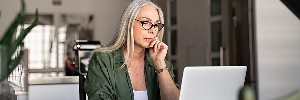 A middle-aged woman researches retirement investment strategies on her laptop.