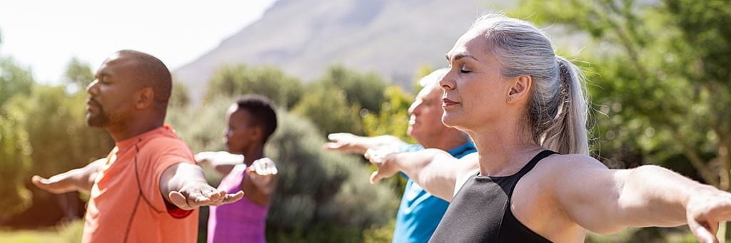 A group of retirees practices yoga during an outdoor class.
