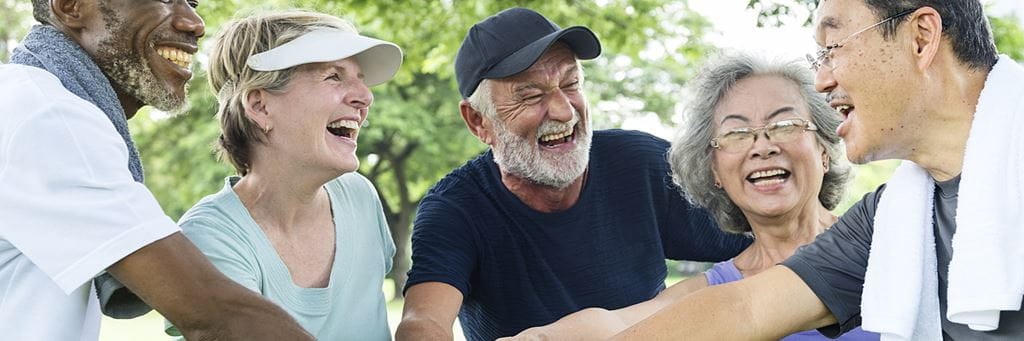 A group of older adults laughing while playing golf in a 55 and over community.