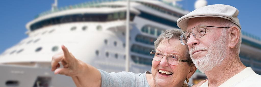 Smiling senior couple with a cruise ship in the background.