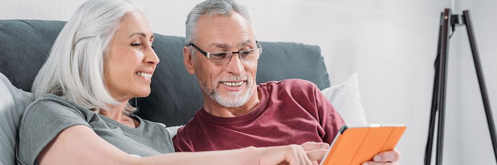 A happy older couple discusses annuity options while sitting in the living room.