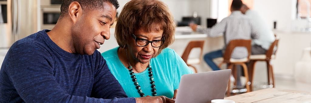 A younger family member assists their senior loved one with signing up for insurance.