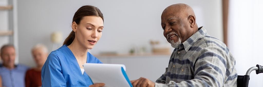 An older adult and a nurse review health care forms.