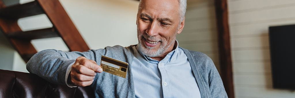 An older man uses a debit card.