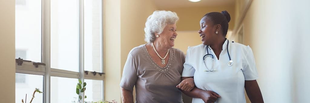An assisted living care professional helps a senior woman with daily activities.
