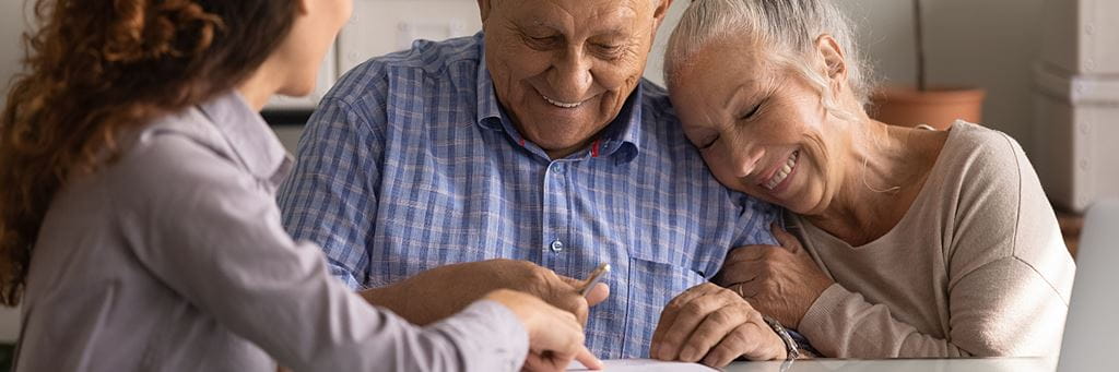 A senior couple reviews an advance health care directive with an insurance agent.