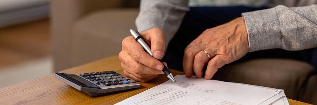 A person reviewing annuity papers with calculator.