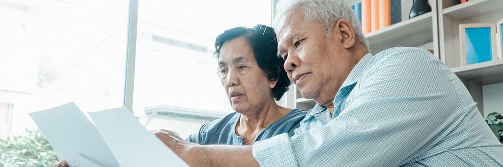 A senior couple reviews financial documents while determining their full retirement age.