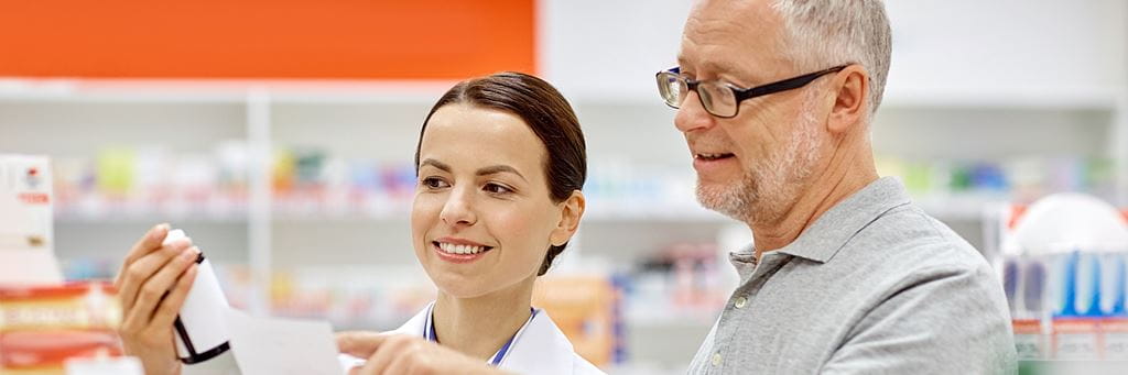A senior man discusses his medication with a female pharmacist.
