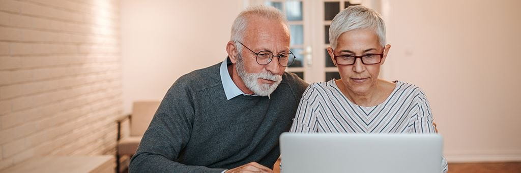 A senior couple uses a laptop to help plan their retirement savings.