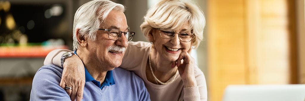 An older couple smiles while budgeting.