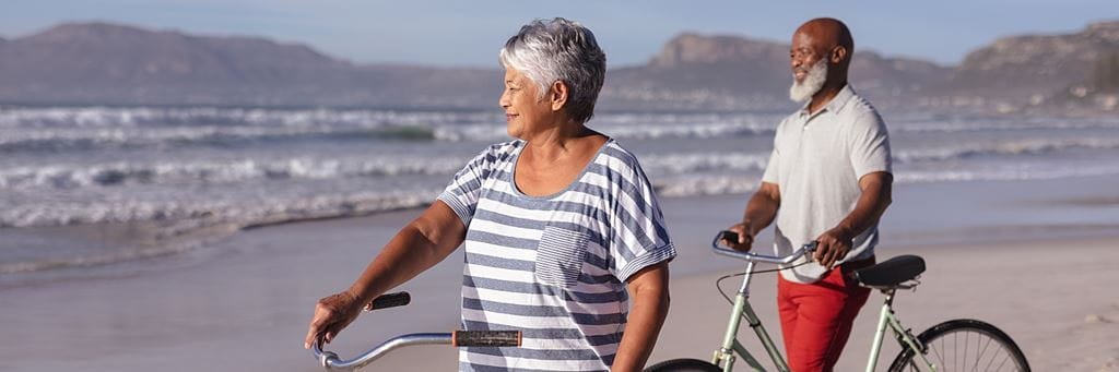 A senior couple with beach bicycles enjoys a sunny day sightseeing at the beach.