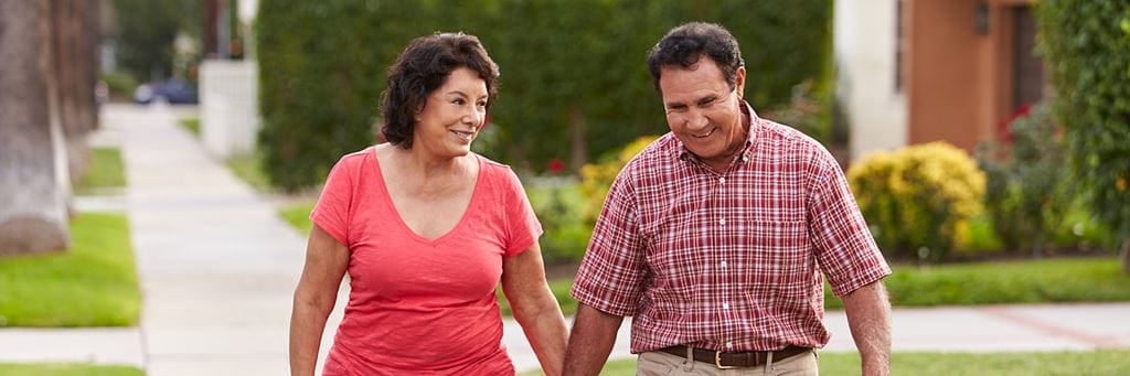A happy older couple walks in their neighborhood.