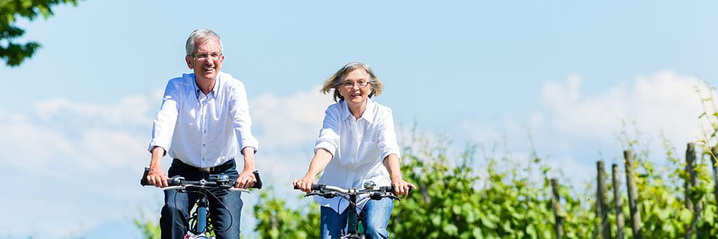 Two seniors bike together on a sunny day.