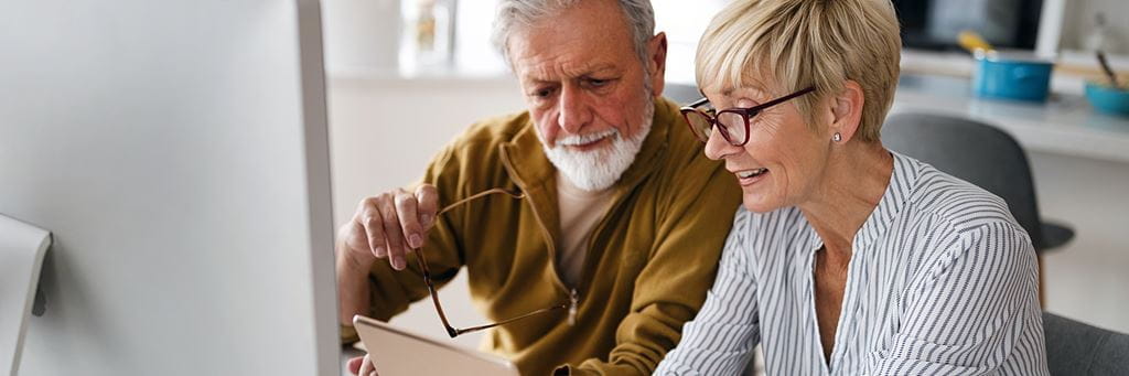 A couple looks at a tablet and computer while researching Original Medicare options.