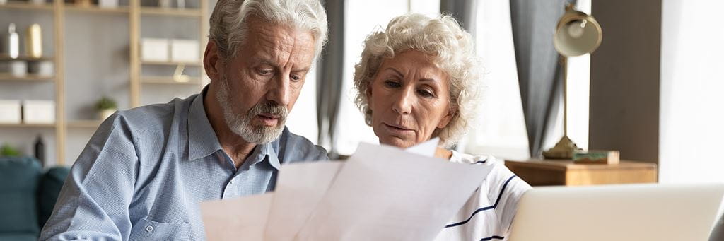 A senior couple reads life insurance paperwork.