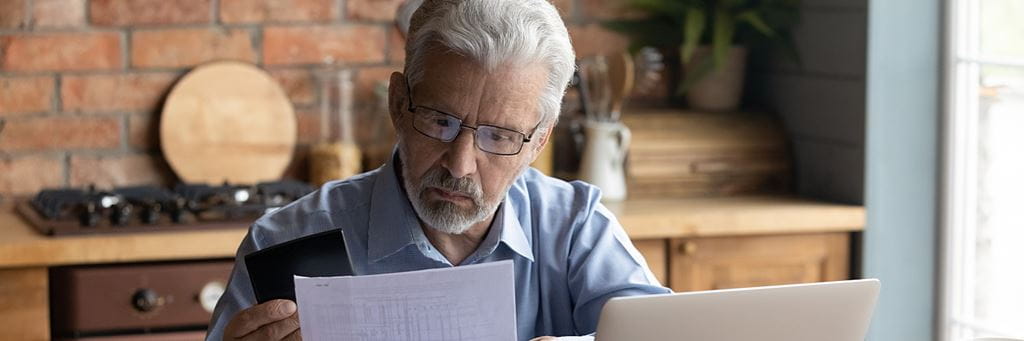 A senior man reviews documents while paying his monthly Medicare premiums.