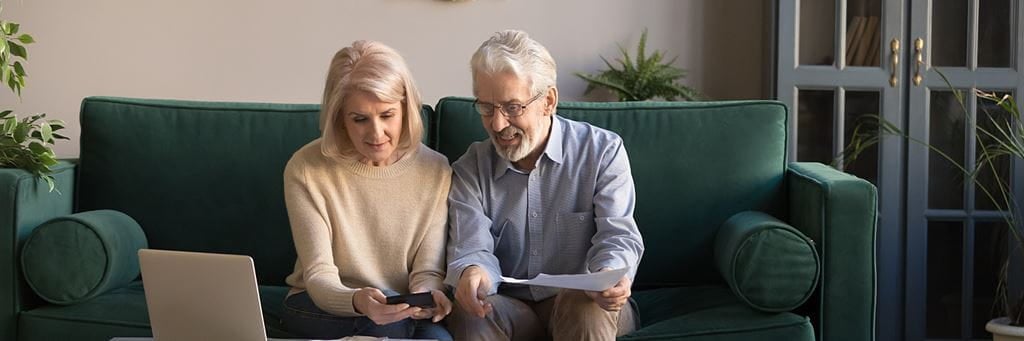 A senior couple reviews documents in their living room to prepare for retirement.