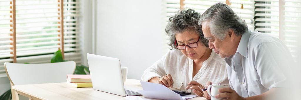 A senior couple reads financial documents to help manage taxes in retirement.