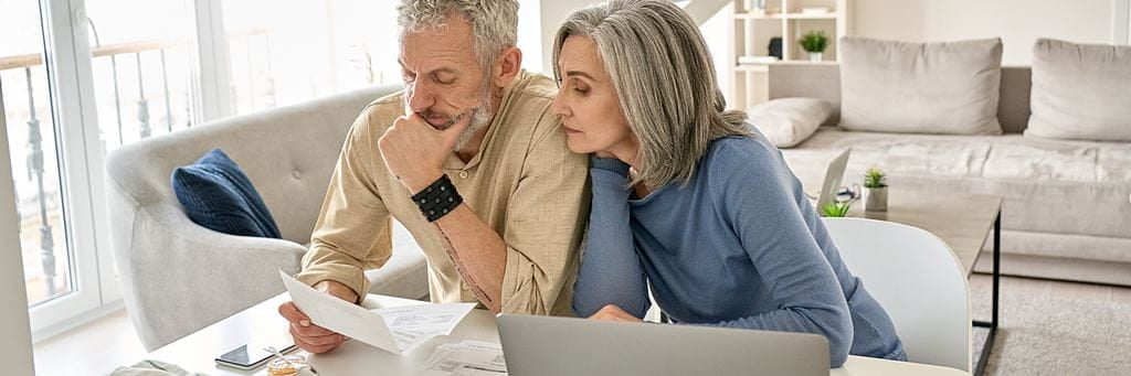 A senior couple reviews financial documents related to their individual retirement accounts.